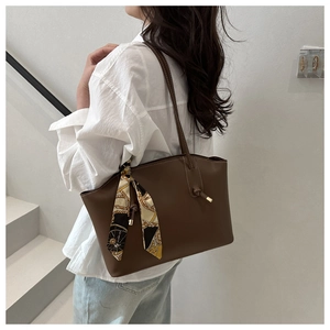 Dettaglio della borsa tote marrone scuro con foulard di seta decorativo sul manico in pelle