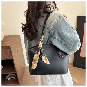Detail of black faux leather tote bag with elegant silk scarf on handle for daily use