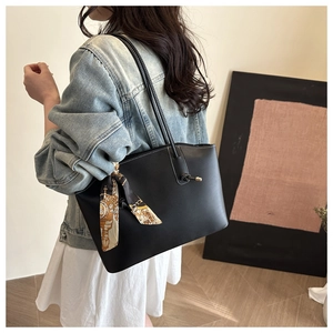 Minimalist black matte leather tote bag with a vintage pattern silk scarf on shoulder