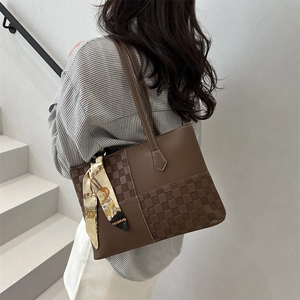 Brown leather tote bag with woven checkerboard panel and silk scarf on modern stairs