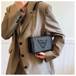 Detail der schwarzen Monogramm-Tasche mit goldener Kette und Lederlogo im Dreieck