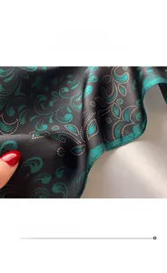 Detailed close-up of emerald green paisley silk scarf with gold dots and fine stitching