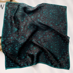 Detail of dark green paisley silk scarf featuring elegant rolled edges and smooth texture