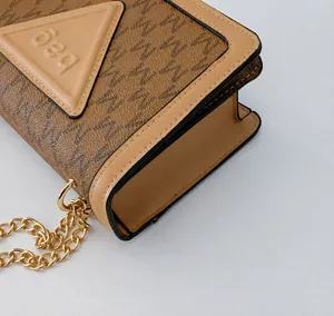 Nahaufnahme der präzisen Nähte und der Goldkette an der braunen M-Muster Handtasche