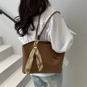 Brown leather tote bag for women with silk scarf accessory shown on shoulder