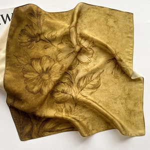 Détail d'un carré de soie ocre avec motifs floraux dessinés à la main et texture lisse