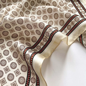 Détail d'un foulard en soie satinée aux motifs mandala bruns et bordures rayées