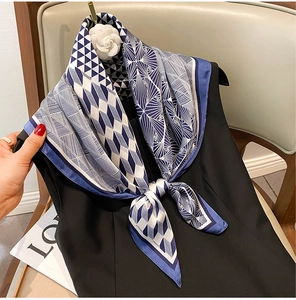 Close-up of elegant blue and white geometric silk scarf tied as a stylish necktie accessory