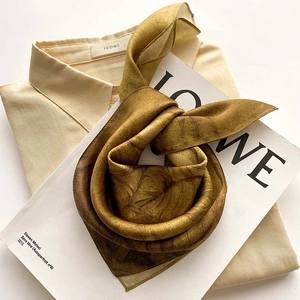 Élégant foulard en soie dorée avec motifs floraux sur un fond de chemise blanche