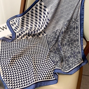 Detail of elegant geometric silk scarf draped on a wooden chair with soft light