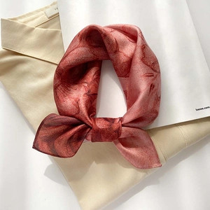 Détail d'un foulard en soie rose à motif floral noué élégamment sur une chemise
