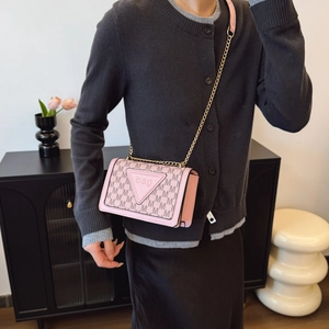 Rosa Umhängetasche mit schwarzem M-Muster und Goldkette, getragen von einem Model