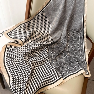 Detail of elegant satin square scarf featuring geometric black and gold cube patterns