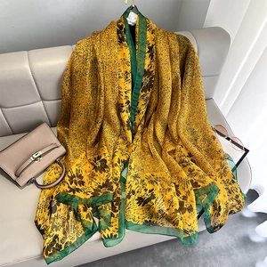 Detail of yellow floral silk scarf with green borders on leather sofa as sun protection shawl
