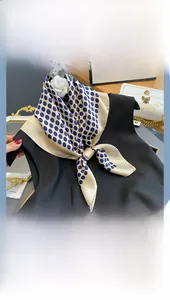 Close-up of beige silk square scarf with blue polka dots tied on black sleeveless top