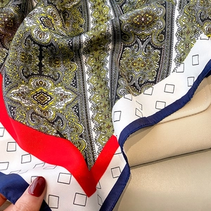 Detalle de un pañuelo de seda con motivos paisley y drapeado elegante sobre fondo de cuero