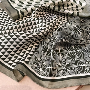 Detailed view of elegant silk scarf featuring black and white geometric cube patterns