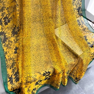 Detail of yellow oil painting style floral silk scarf with green stitched edges