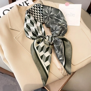 Detail of silk-like scarf with green and beige geometric patterns on a suit