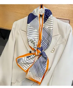 Dettaglio di una sciarpa di seta a pois annodata sul colletto di un blazer beige