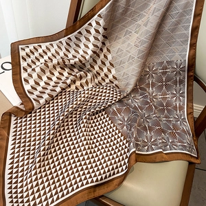Detailed view of geometric pattern silk scarf draped on a leather chair with props