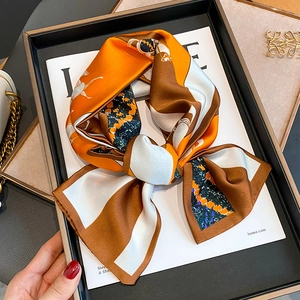 Vintage horse print orange silk scarf tied in a bow on a luxury display tray