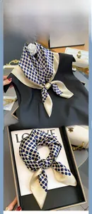 Close-up of champagne silk scarf with navy polka dots and elegant satin sheen texture