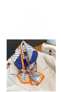 Dettaglio di un foulard in seta a pois annodato su un colletto di abito beige con bordi arancio