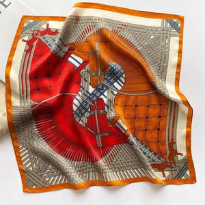 Detail of silk scarf showing equestrian horse head patterns and hand-rolled orange edges