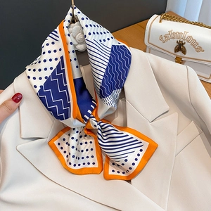 Sciarpa di seta a pois con bordo arancione su un blazer, accessorio chic francese