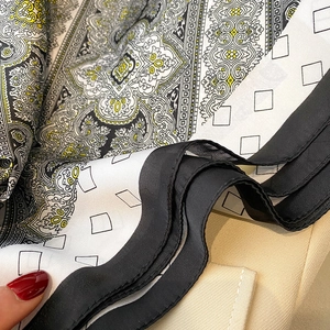 Detalle de pañuelo de seda paisley vintage con bordes enrollados a mano y estampado amarillo