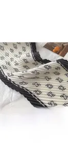 Détail de la texture plissée et des motifs géométriques noirs sur l'écharpe en soie
