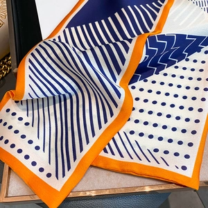 Dettaglio di sciarpa in seta con pois blu, motivi ondulati e bordi arancioni brillanti