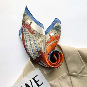 Detail of silk scarf with orange horse print tucked into a beige blazer collar