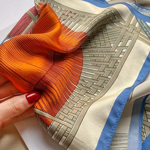 Close-up of hand-rolled edges and twill silk texture on orange and blue scarf