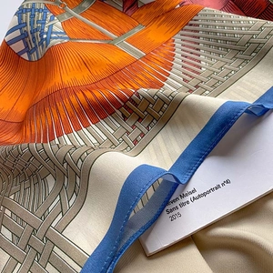 Macro view of bright blue silk square scarf featuring hand-rolled edges and intricate prints