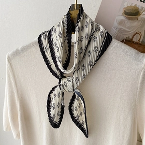 Élégant foulard plissé noir et blanc avec imprimé géométrique sur un pull en maille blanc