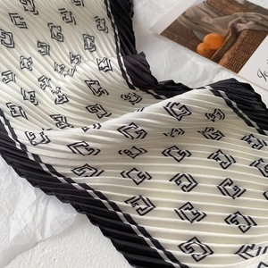Détail d'un foulard en soie plissé avec motif géométrique noir et blanc et imprimés G