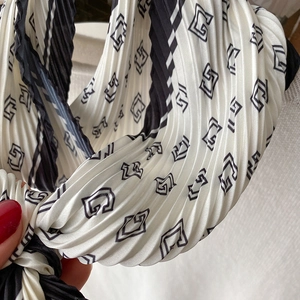 Gros plan d'un foulard plissé en soie avec des motifs géométriques noirs et blancs