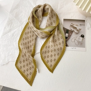 Détail d'un foulard plissé beige avec bords vert olive et motif géométrique élégant