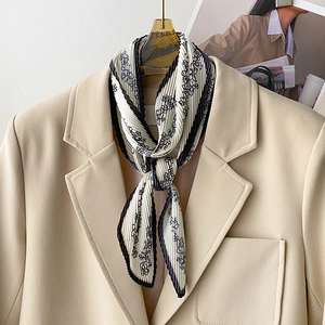 Detail of pleated floral skinny scarf styled as a necktie on a beige blazer jacket