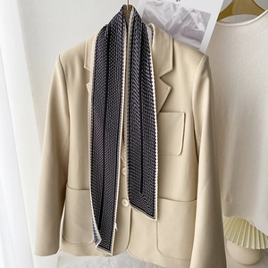 Dettaglio di una sciarpa a righe con pois bianchi e neri su un colletto di blazer beige