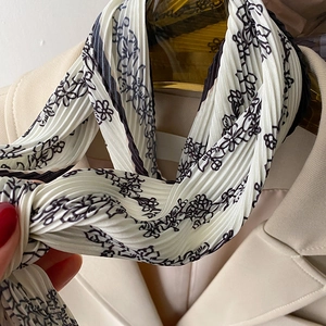 Detail of floral pleated scarf on golden hanger paired with beige professional suit