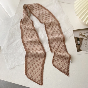 Détail d'un foulard plissé café et beige avec motif G géométrique sur papier blanc
