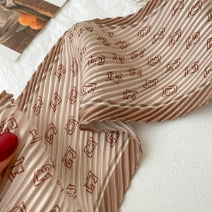 Vue détaillée d'un foulard plissé marron avec impression de motifs géométriques