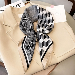 Elegant black and white geometric silk scarf tied as a bow on a beige blazer