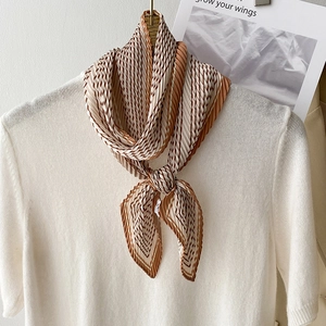 Elegante sciarpa plissettata a righe marroni e beige su un top in maglia bianca