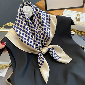 Champagne gold silk scarf with navy polka dots displayed on an elegant lifestyle setting