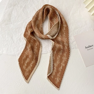 Detail of terracotta pleated silk scarf with white floral patterns and beige ruffled edges