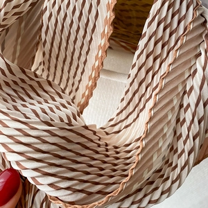Dettaglio di sciarpa plissettata a righe marroni e beige con fine trama a fisarmonica